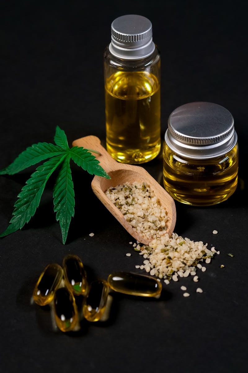 A set of CBD products including oil, capsules, hemp seeds, and a cannabis leaf, presented on a dark backdrop.