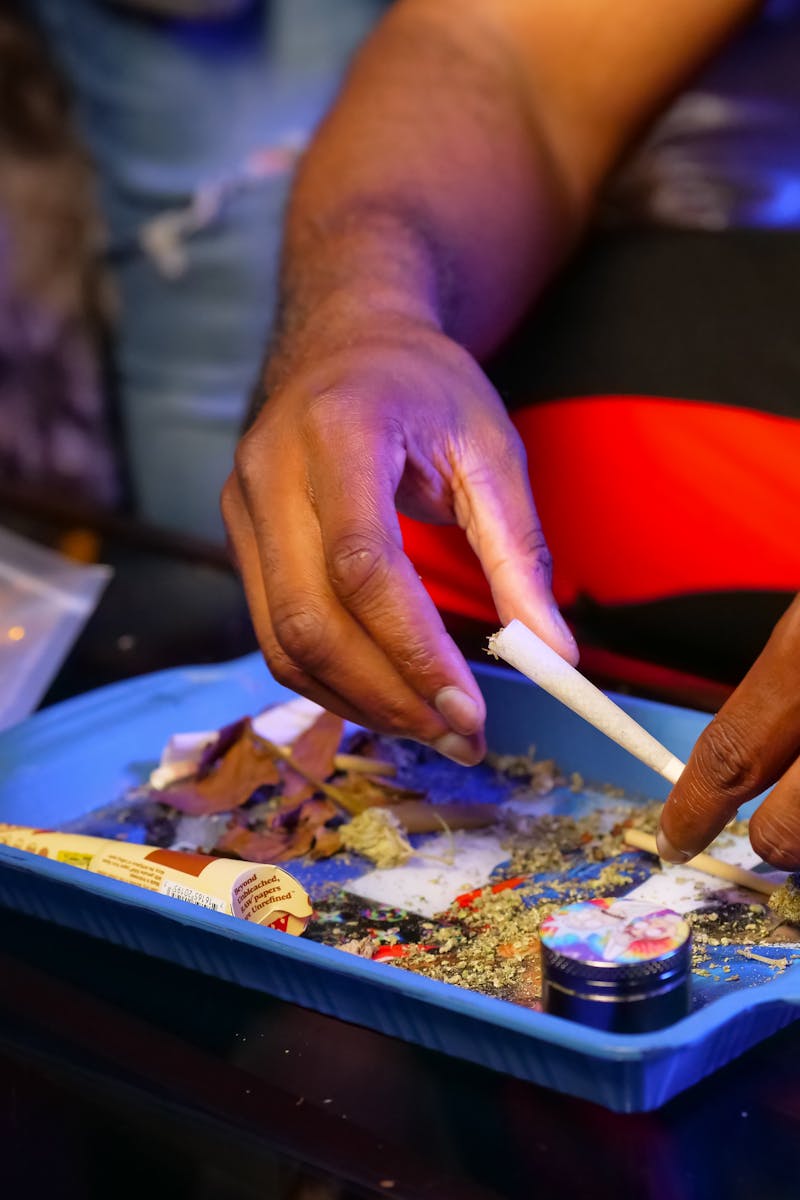 Hands preparing a cannabis joint on a tray, highlighting the process of rolling.
