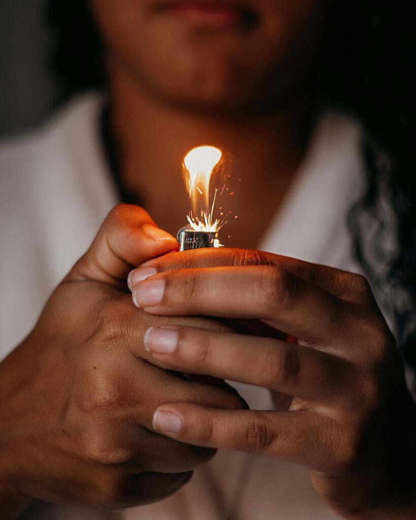 A close-up view of a person igniting a lighter, showcasing sparks and flame.